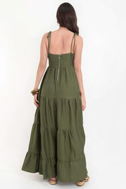 Maxi vestido de escote v con cortes y plisados decorativos, tirantes delgados con nudo amarrable, corte en a, bajo con capas de olanes y cierre posterior con cremallera visible en contraste.
