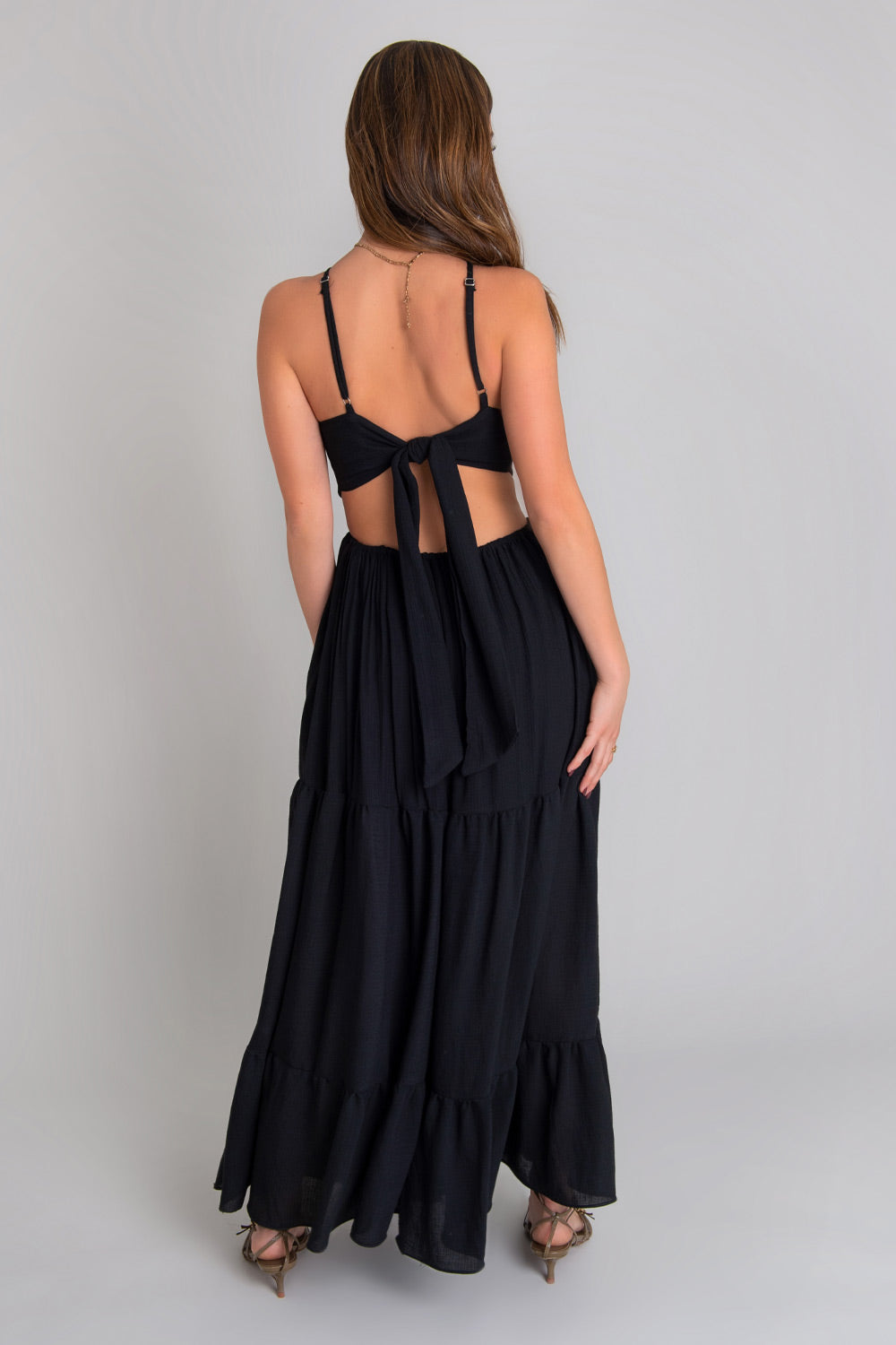 Maxi vestido de cuello halter con tirantes delgados ajustables, corte en a, bajo con capas de olanes, cut out en costados y espalda. Detalle de rib elástico en cintura y cierre posterior con lazo amarrable.