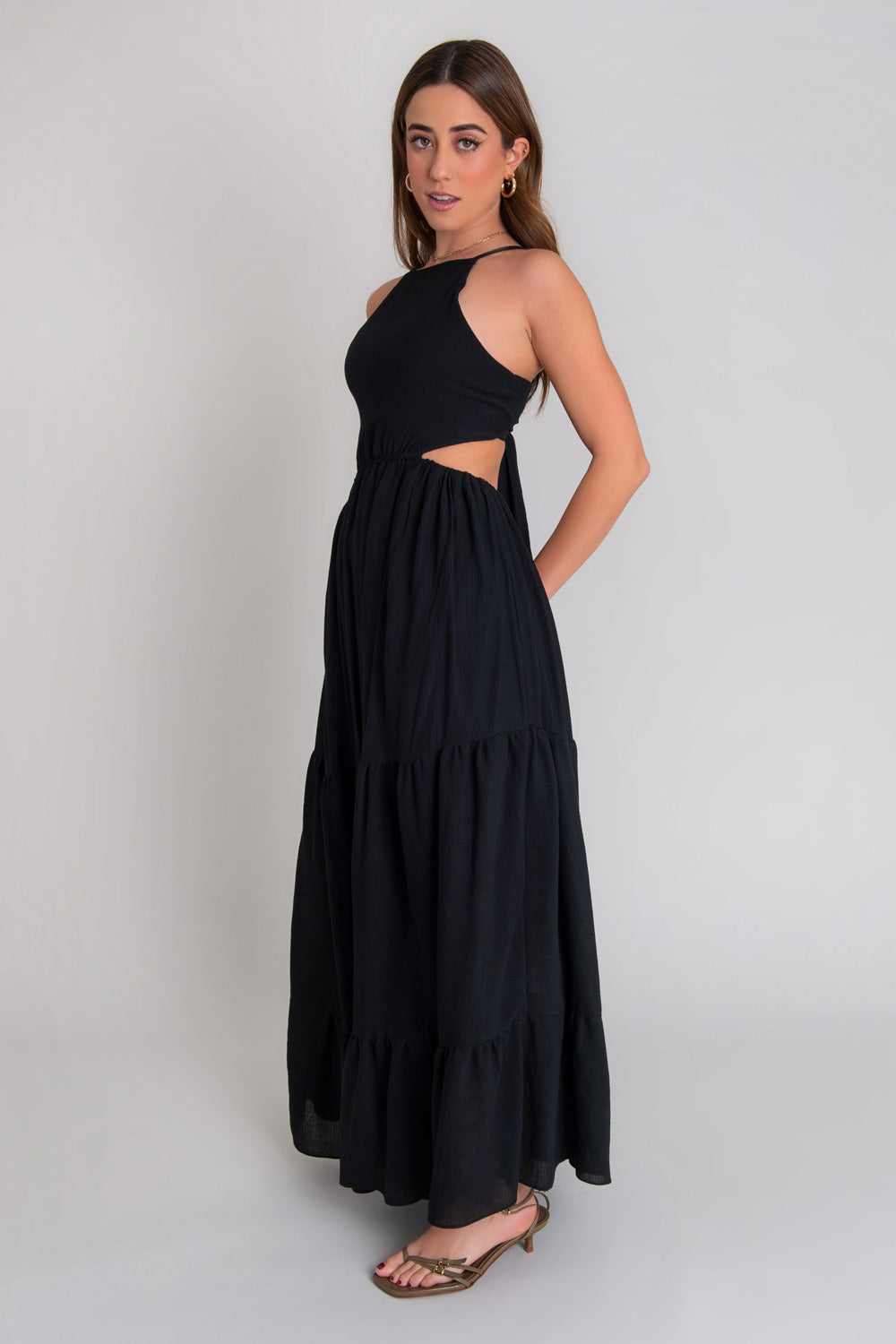 Maxi vestido de cuello halter con tirantes delgados ajustables, corte en a, bajo con capas de olanes, cut out en costados y espalda. Detalle de rib elástico en cintura y cierre posterior con lazo amarrable.