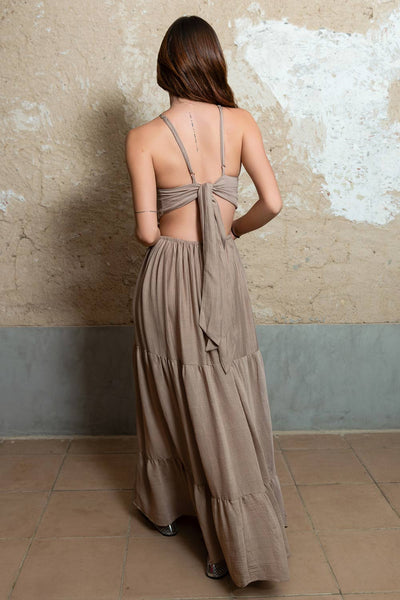 Maxi vestido de cuello halter con tirantes delgados ajustables, corte en a, bajo con capas de olanes, cut out en costados y espalda. Detalle de rib elástico en cintura y cierre posterior con lazo amarrable.