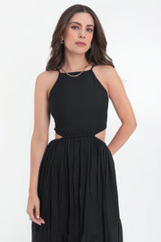 Maxi vestido de cuello halter con tirantes delgados ajustables, corte en a, bajo con capas de olanes, cut out en costados y espalda. Detalle de rib elástico en cintura y cierre posterior con lazo amarrable.