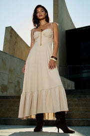 Maxi vestido de corte en a, tirantes delgados con nudo amarrables, escote corazón con cortes y detalles plisados. Cierre posterior con cremallera visible en contraste y olanes en borde de bajo.