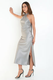 Maxi vestido satinado de fit recto, cuello halter cruzado con lazo amarrable posterior, escote en espalda y cierre posterior con cremallera oculta. Detalle de abertura lateral en bajo.