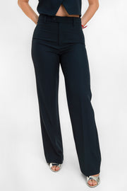 Pantalón ajustado de cintura alta con pretina y trabillas, bolsillos delanteros, fit recto, raya frontal y posterior. Cierre frontal con botón y cremallera oculta. 