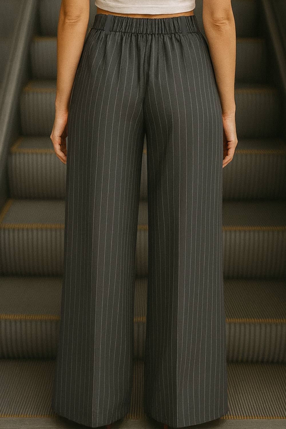 Pantalón de estampado rayas, fit palazzo, cintura alta con pretina elástica posterior, trabillas, bolsillos delanteros y pinzas frontales. Cierre frontal con botón y cremallera oculta.