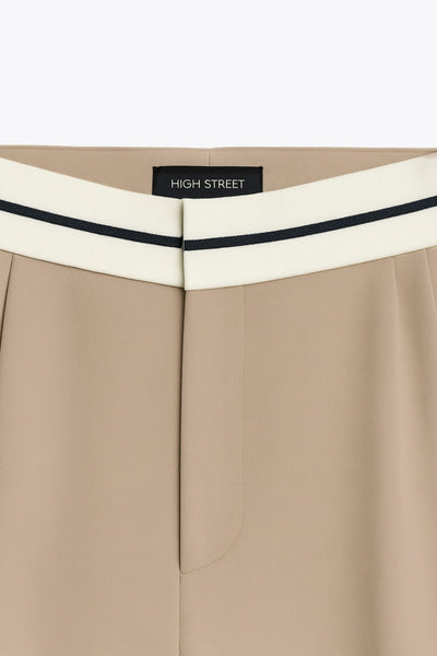 Pantalón de fit wide leg, pinzas frontales, cintura media con detalle de pretina en contraste, bolsillos delanteros y vivos decorativos posteriores. Detalle de raya frontal y posterior. Cierre frontal con broche y cremallera ocultos.