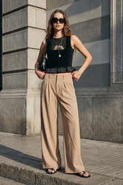 Pantalón de fit palazzo, cintura alta con trabillas, pinzas frontales, bolsillos delanteros y vivos decorativos posteriores, raya frontal y posterior. Cierre frontal con broche y cremallera ocultos.