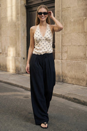 Pantalón de fit palazzo, cintura alta con trabillas, pinzas frontales, bolsillos delanteros y vivos decorativos posteriores, raya frontal y posterior. Cierre frontal con broche y cremallera ocultos.