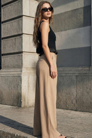 Pantalón de fit palazzo, cintura alta con trabillas, pinzas frontales, bolsillos delanteros y vivos decorativos posteriores, raya frontal y posterior. Cierre frontal con broche y cremallera ocultos.