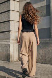 Pantalón de fit palazzo, cintura alta con trabillas, pinzas frontales, bolsillos delanteros y vivos decorativos posteriores, raya frontal y posterior. Cierre frontal con broche y cremallera ocultos.