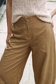 Pantalón de fit balloon, cintura media con pretina elástica posterior, bolsillos delanteros, cierre frontal con broche y cremallera ocultos. Detalle de bajo abotonado con pinzas.
