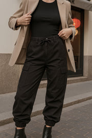 Pantalón cargo de cintura alta elástica con jareta frontal ajustable, fit amplio, plisados decorativos en rodillas, bolsillos delanteros, laterales cargo con cartera y traseros de parche. Detalle de bajo con jaretas ajustables, cierre frontal con botón y cremallera oculta.