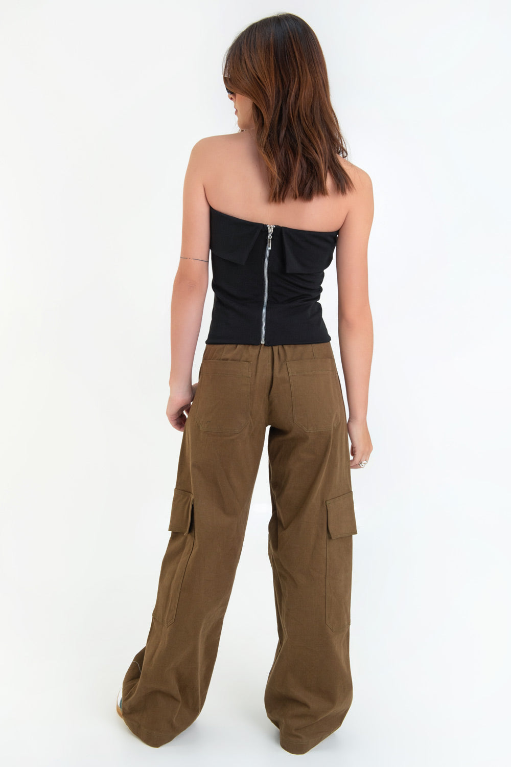 Pantalón cargo de fit wide leg, cintura media con pretina elástica posterior, trabillas, bolsillos delanteros, laterales cargo con cartera y traseros de parche. Detalle de bolsillo decorativo frontal con cremallera, cierre frontal con cremallera oculta y botón en contraste.