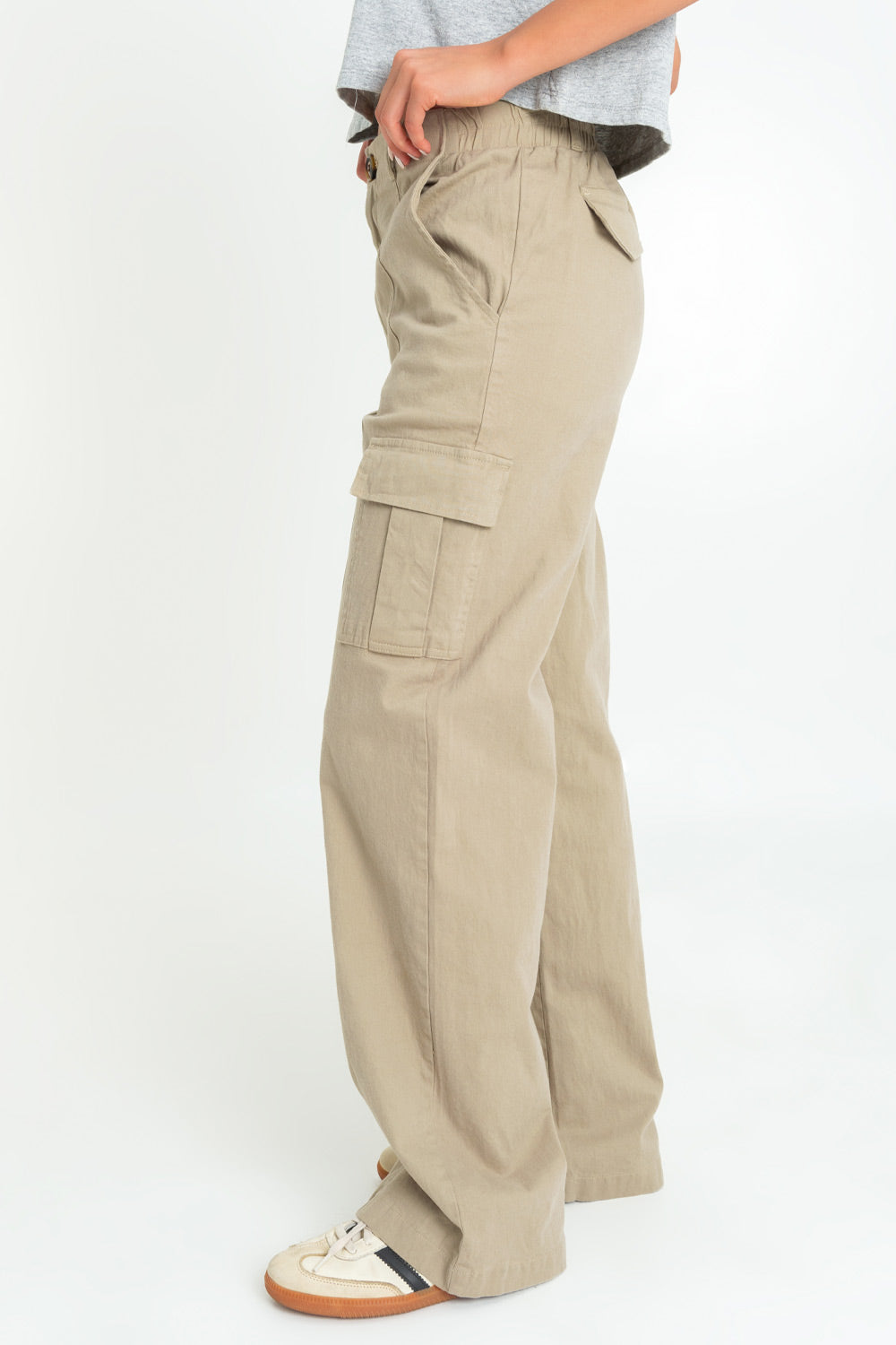 Pantalón cargo de fit wide leg, cintura alta con pretina y trabillas, bolsillos delanteros y laterales cargo con cartera, bolsillos decorativos posteriores con cartera, pretina elástica posterior y cierre frontal con botón y cremallera oculta. Detalle de raya frontal