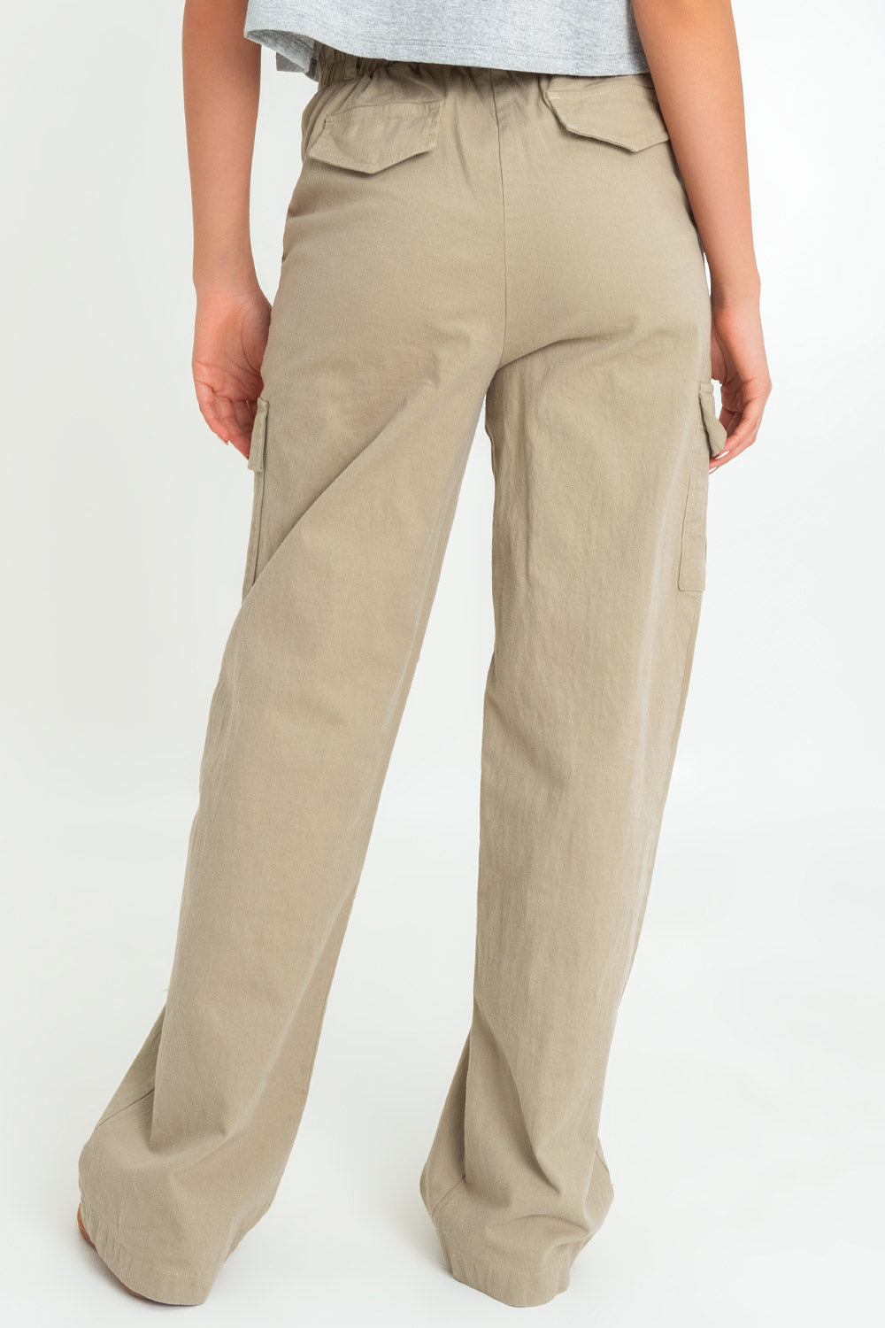 Pantalón cargo de fit wide leg, cintura alta con pretina y trabillas, bolsillos delanteros y laterales cargo con cartera, bolsillos decorativos posteriores con cartera, pretina elástica posterior y cierre frontal con botón y cremallera oculta. Detalle de raya frontal