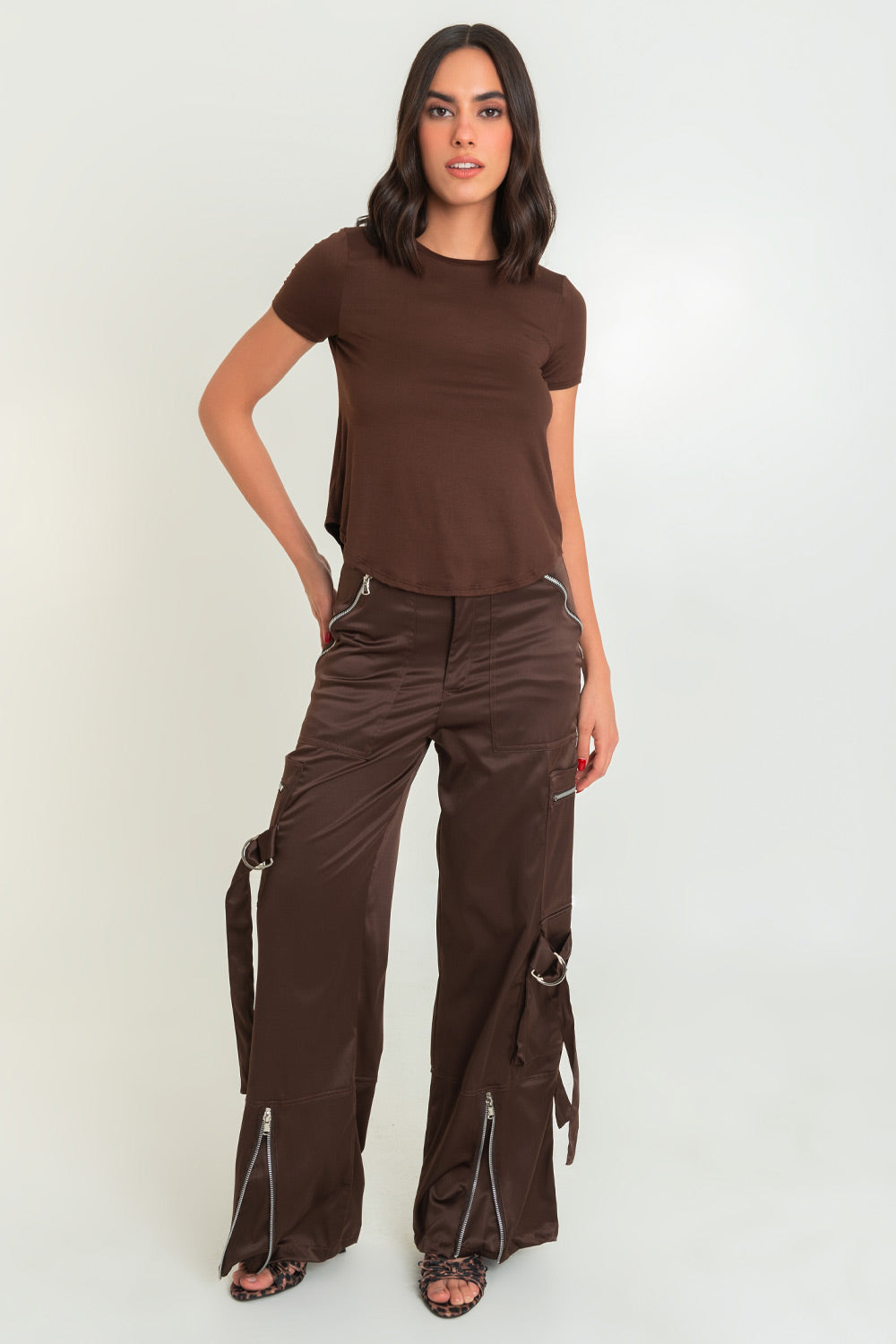 Pantalón satinado de cintura alta, fit wide leg, bolsillos delanteros y traseros de parche. Detalle de abertura frontal en bajo con cremalleras, bolsillos laterales cargo con cremalleras, trabillas y cartera. Cierre frontal con botón y cremallera oculta.