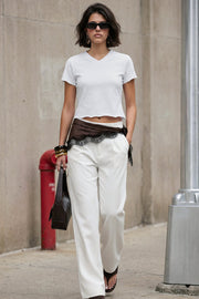 Pantalón de fit wide leg, pinzas frontales, bolsillos delanteros, cintura alta con pretina y trabillas. Detalle de vivo decorativo posterior, cierre con botón y cremallera oculta.
