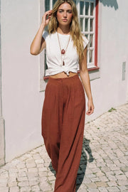 Pantalón fluido de cintura alta con pretina y trabillas, fit wide leg, pinzas frontales, bolsillos delanteros, detalle de raya frontal y posterior. Cierre frontal con botón y cremallera oculta.