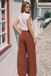 Pantalón fluido de cintura alta con pretina y trabillas, fit wide leg, pinzas frontales, bolsillos delanteros, detalle de raya frontal y posterior. Cierre frontal con botón y cremallera oculta.