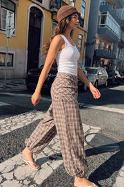 Pantalón fluido de fit palazzo, estampado cuadros, cintura media con pretina elástica, plisados en costado y detalle de pareo decorativo con nudo lateral.