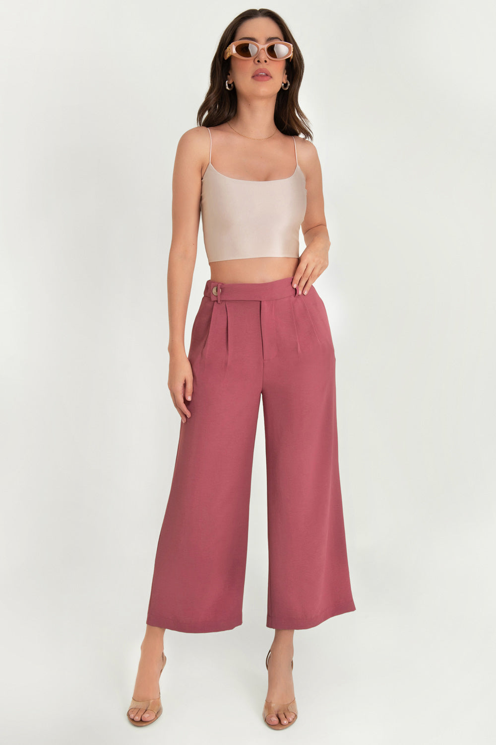 Pantalón de fit culotte, cintura alta con pretina elástica posterior y trabillas, pinzas frontales, bolsillos delanteros y vivos decorativos posteriores. Cierre frontal con cremallera oculta y trabilla con botón en contraste.