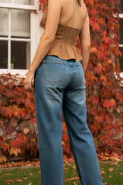 Pantalón de denim, fit recto, cintura alta con pretina y trabillas, detalle de rotos en bajo, bolsillos delanteros y traseros de parche. Cierre frontal con botón y cremallera oculta.