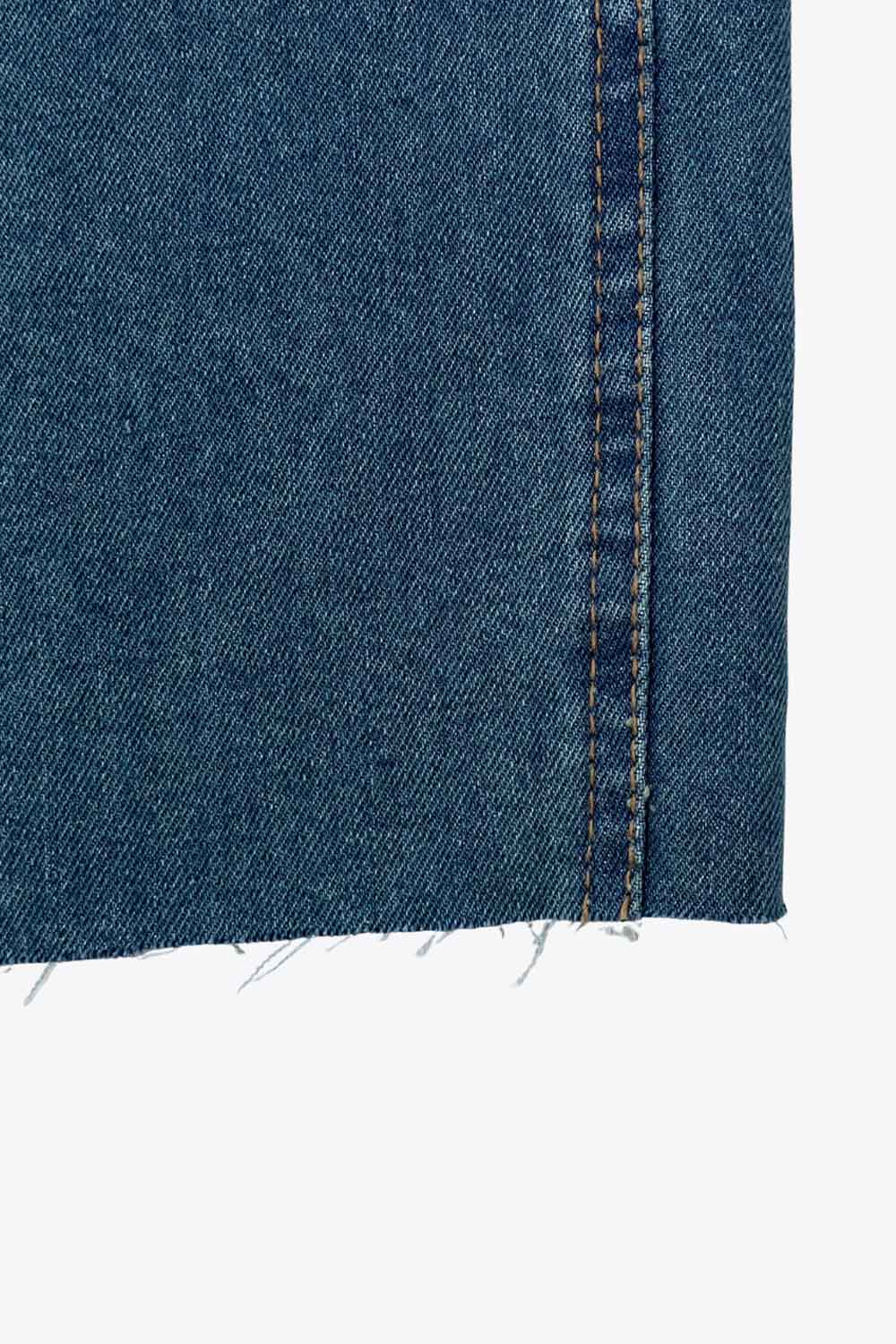 Pantalón de denim, fit recto, cintura alta con pretina y trabillas, detalle de rotos en bajo, bolsillos delanteros y traseros de parche. Cierre frontal con botón y cremallera oculta.