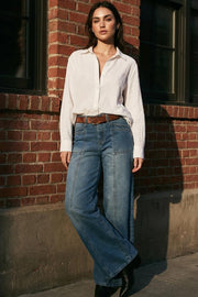 Pantalón de denim, fit wide leg, tiro medio con pretina y trabillas, bolsillos delanteros y traseros de parche. Cierre con botón y cremallera oculta. Detalle de costuras decorativas frontales.