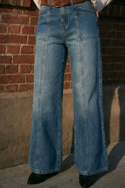 Pantalón de denim, fit wide leg, tiro medio con pretina y trabillas, bolsillos delanteros y traseros de parche. Cierre con botón y cremallera oculta. Detalle de costuras decorativas frontales.