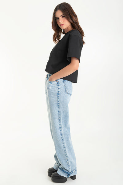 Pantalón de denim, fit wide leg, cintura alta con pretina y trabillas, bolsillos delanteros y traseros de parche. Cierre frontal con botón y cremallera oculta. Detalle de rotos y doblez en bajo.