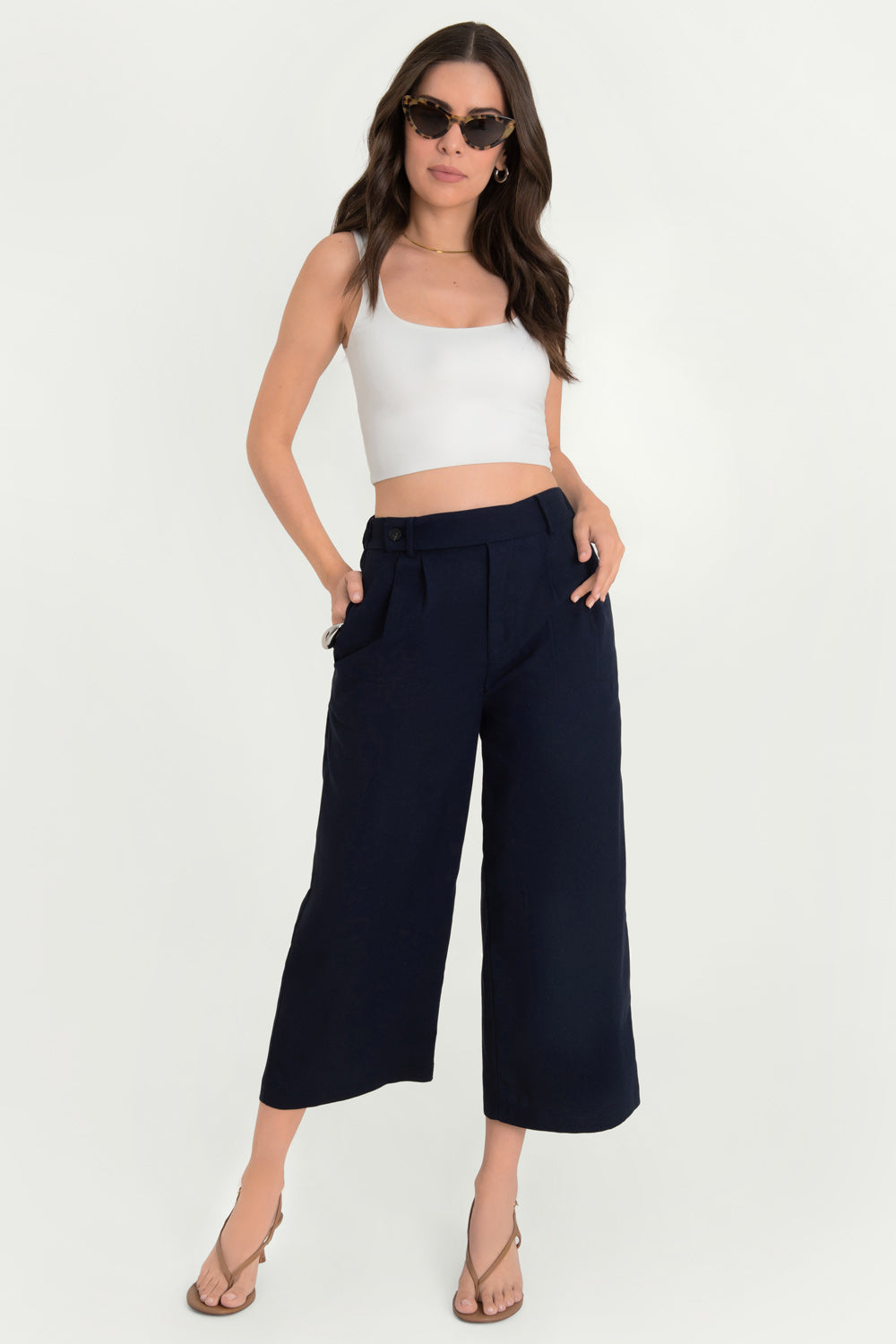 Pantalón de fit culotte, cintura alta con pretina elástica posterior y trabillas, pinzas frontales, bolsillos delanteros y vivos decorativos posteriores. Cierre frontal con cremallera oculta y trabilla con botón.