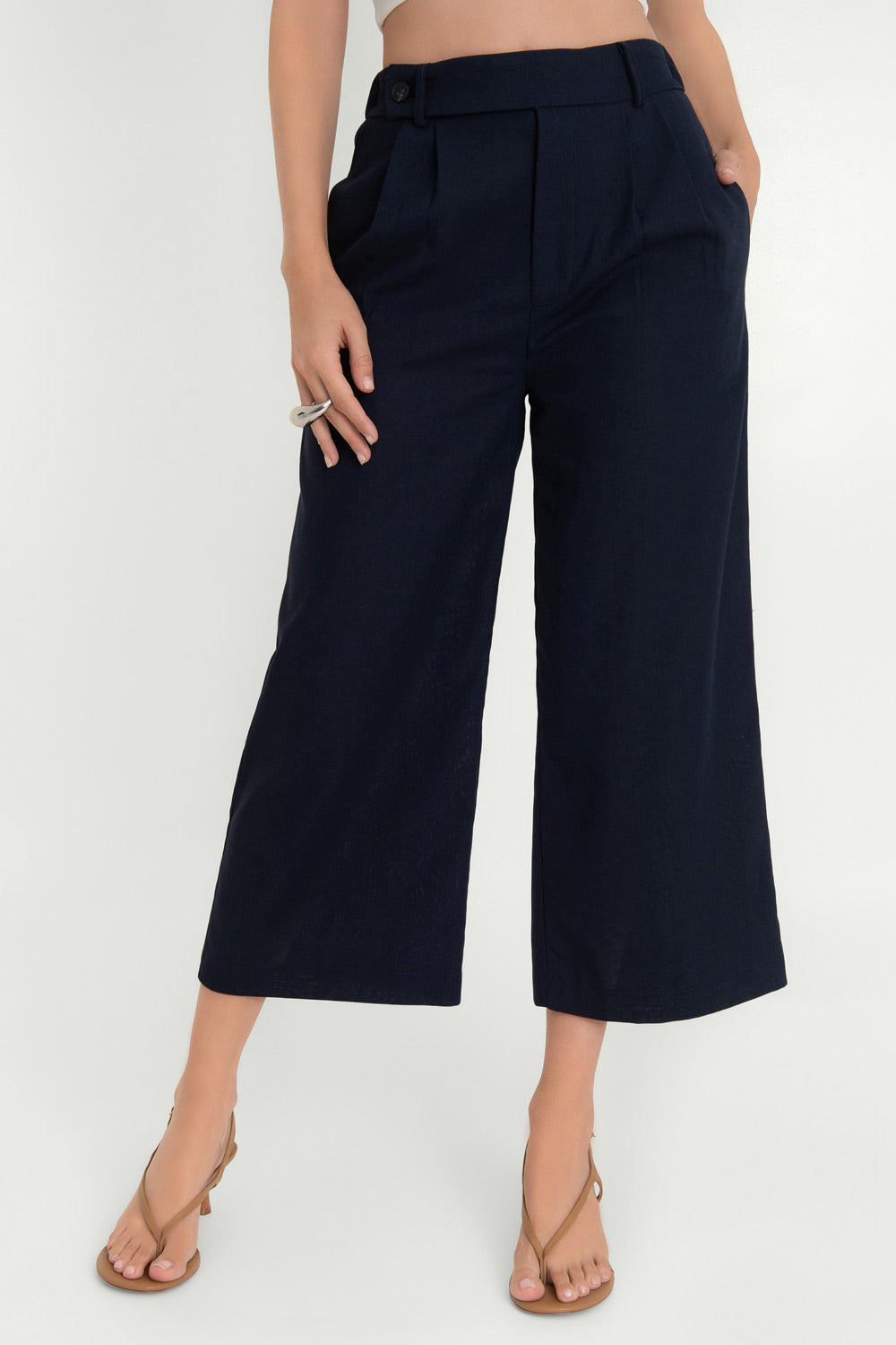 Pantalón de fit culotte, cintura alta con pretina elástica posterior y trabillas, pinzas frontales, bolsillos delanteros y vivos decorativos posteriores. Cierre frontal con cremallera oculta y trabilla con botón.