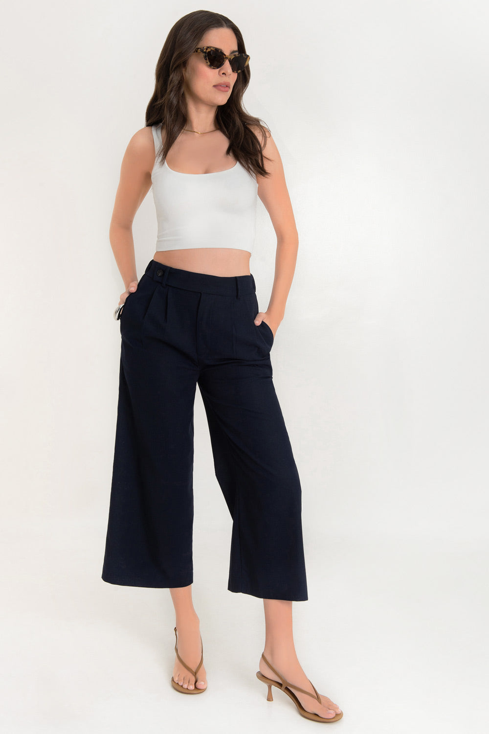 Pantalón de fit culotte, cintura alta con pretina elástica posterior y trabillas, pinzas frontales, bolsillos delanteros y vivos decorativos posteriores. Cierre frontal con cremallera oculta y trabilla con botón.