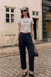 Pantalón de fit recto, cintura alta con pretina elástica posterior, pinzas frontales, bolsillos delanteros, vivo decorativo posterior y doblez en bajo. Cierre frontal con broche y cremallera ocultos.