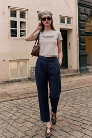 Pantalón de fit recto, cintura alta con pretina elástica posterior, pinzas frontales, bolsillos delanteros, vivo decorativo posterior y doblez en bajo. Cierre frontal con broche y cremallera ocultos.