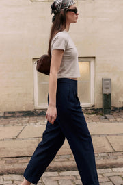 Pantalón de fit recto, cintura alta con pretina elástica posterior, pinzas frontales, bolsillos delanteros, vivo decorativo posterior y doblez en bajo. Cierre frontal con broche y cremallera ocultos.