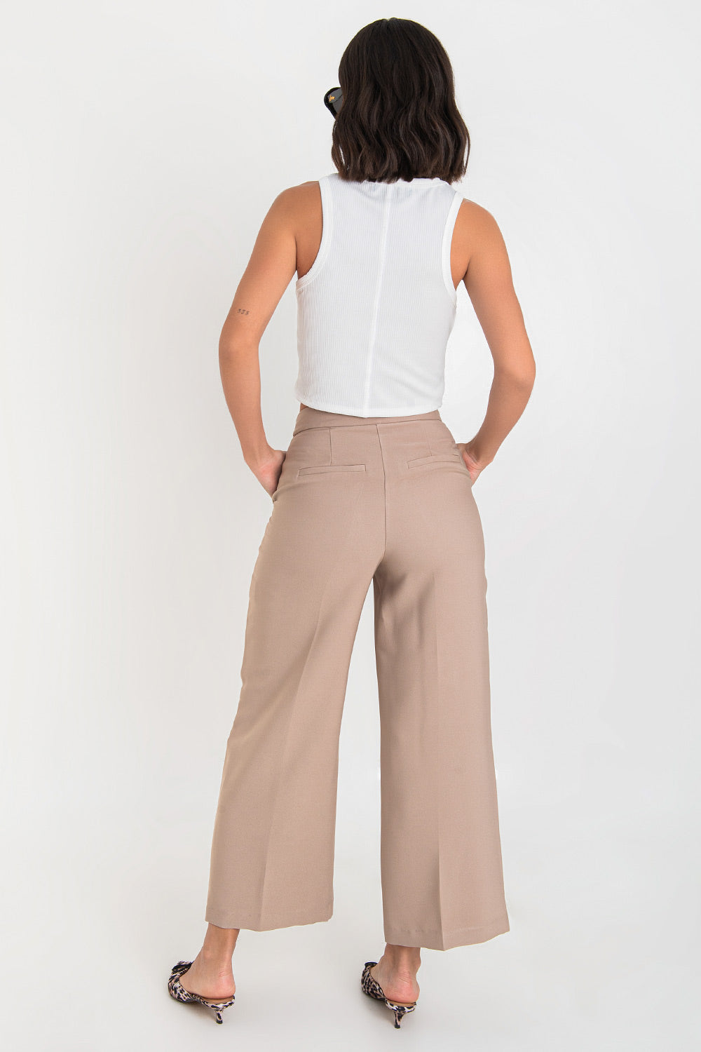 Pantalón de fit wide leg, cintura alta con pretina, bolsillos delanteros y vivos decorativos posteriores, detalle de raya frontal y posterior. Cierre frontal con broche y cremallera oculta.