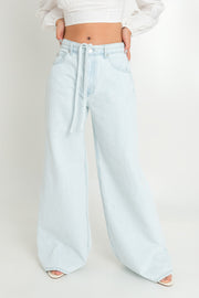 Pantalón de denim wide leg fit, bolsillos delanteros y traseros de parche, cintura alta con pretina, trabillas y cinturón amarrable del mismo tejido. Cierre frontal con botón y cremallera oculta.