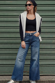 Pantalón wide leg de denim, cintura media con pretina y trabillas, bolsillos delanteros y traseros de parche con bordado de estrella. Cierre frontal con botón y cremallera oculta.