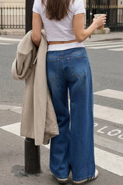 Pantalón wide leg de denim, cintura alta con pretina elástica en constraste, bolsillos delanteros y posteriores de parche. Cierre frontal con botones y cremallera oculta.