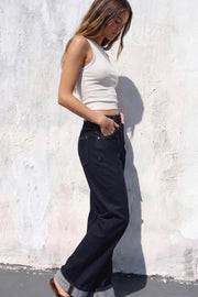 Pantalón de denim, fit recto, tiro alto, pretina con trabillas, bolsillos delanteros y traseros de parche. Cierre frontal con botón y cremallera oculta. Detalle de doblez en bajo.