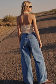 Pantalón de denim, fit wide leg, tiro alto, pretina con trabillas, bolsillos delanteros y traseros de parche. Cierre frontal con botón y cremallera oculta.