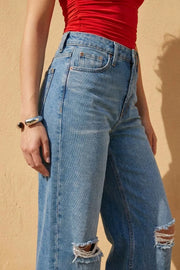 Pantalón wide leg de denim con rotos, tiro alto, bolsillos delanteros y traseros de parche. Cierre con botón y cremallera oculta. Detalle de rotos en bajo.