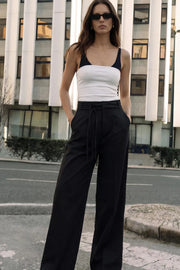 Pantalón de fit wide leg, cintura alta con pretina, trabillas y doble lazo amarrable, pinzas frontales y bolsillos delanteros. Cierre frontal con broche y cremallera ocultos.