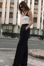 Pantalón de fit wide leg, cintura alta con pretina, trabillas y doble lazo amarrable, pinzas frontales y bolsillos delanteros. Cierre frontal con broche y cremallera ocultos.
