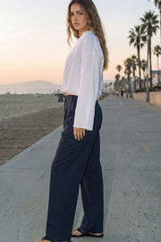 Pantalón de fit wide leg, cintura alta con pretina, trabillas y doble lazo amarrable, pinzas frontales y bolsillos delanteros. Cierre frontal con broche y cremallera ocultos.