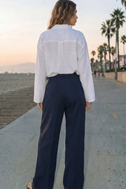 Pantalón de fit wide leg, cintura alta con pretina, trabillas y doble lazo amarrable, pinzas frontales y bolsillos delanteros. Cierre frontal con broche y cremallera ocultos.