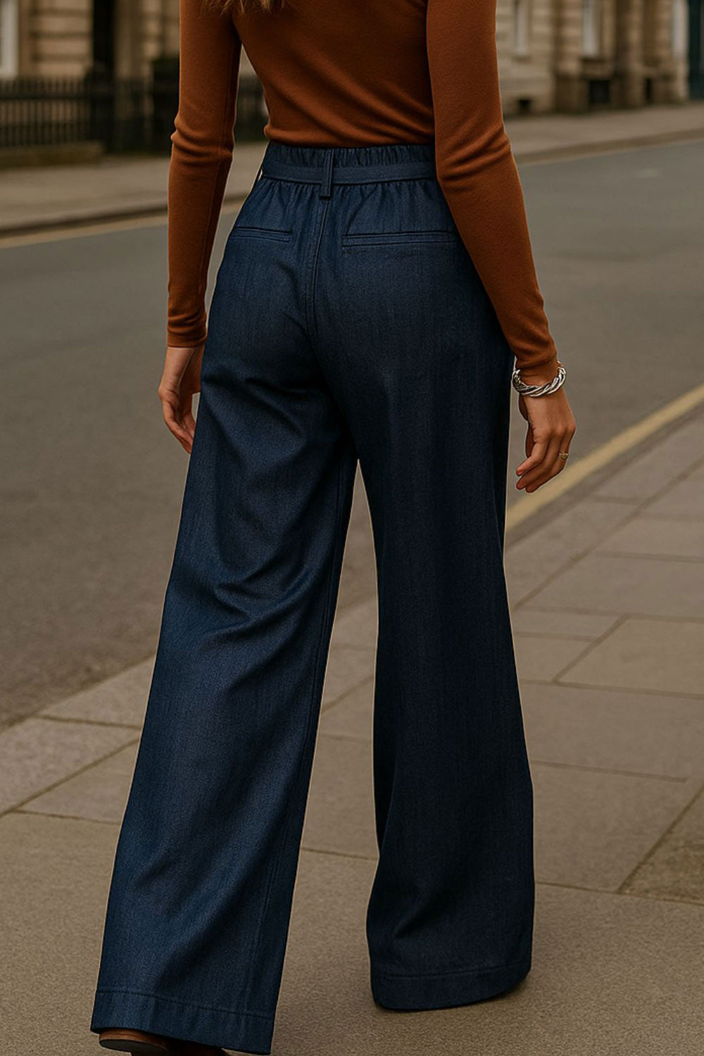 Pantalón de fit wide leg, cintura alta con pretina elástica posterior y trabillas, cinturón del mismo tejido con hebilla en contraste, pinzas frontales, vivos decorativos posteriores y cierre frontal con cremallera oculta.