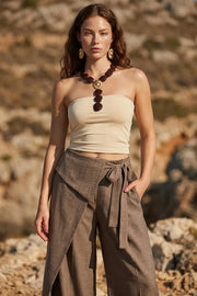 Pantalón de fit wide leg, bolsillos delanteros, cintura alta y cruce frontal con lazo amarrable lateral. Detalle decorativo en pretina frontal.