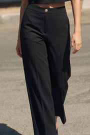 Pantalón de fit amplio, cintura media con pretina, bolsillos delanteros y vivos decorativos posteriores. Detalle de raya frontal y posterior. Cierre frontal con botón y cremallera oculta.